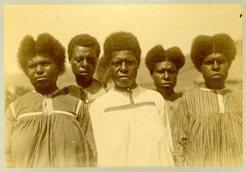 Alfred Cort Haddon took this photograph of a group of women on the Island of Mabuaig in August 1888. The women are wearing the ‘hideous calico gowns’ missionaries  introduced. Photo credit: Haddon, 1888, Calico gowns, Mabuiag, Torres Strait. British Museum number Oc,B41.23. Reproduced here under a NonCommercial-ShareAlike 4.0 International (CC BY-NC-SA 4.0) license. © The Trustees of the British Museum. Alt Text: Ciarán  Walsh, curator.ie.
